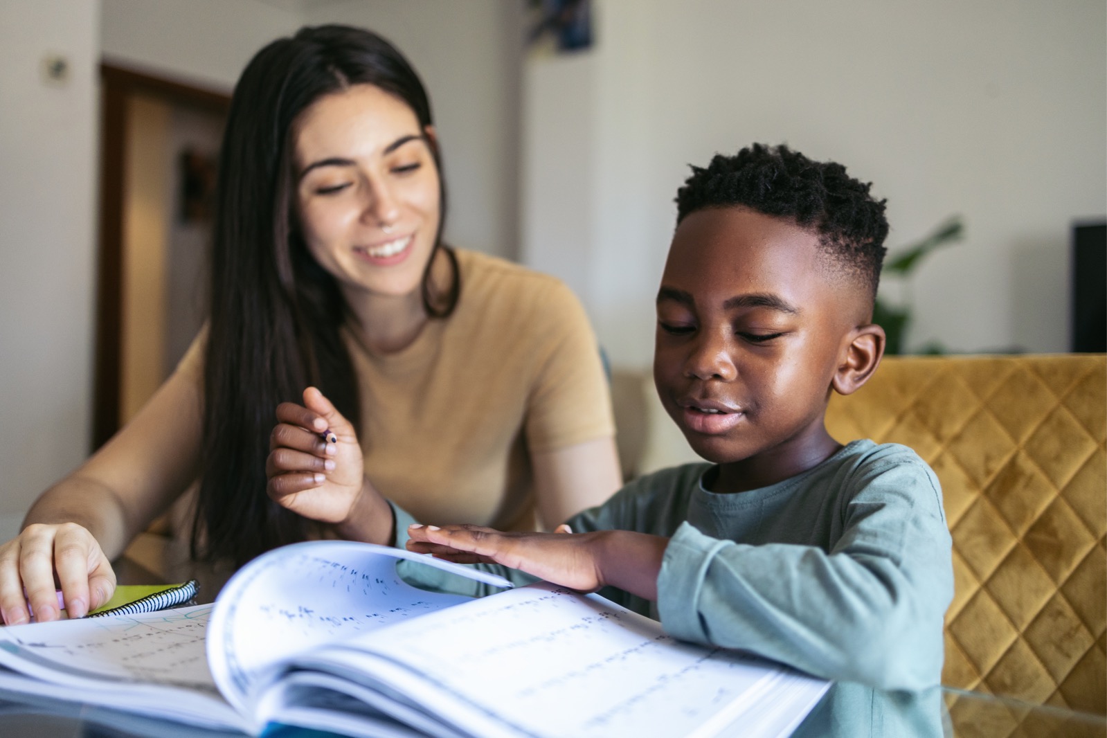 Little boy doing homework at home with female adult